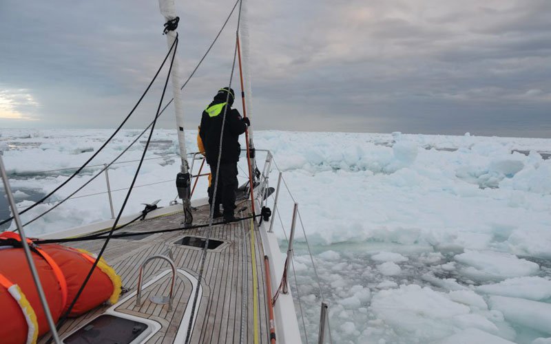 Sailing yacht equipped with Turtle-Pac flexible bladder tanks and liferaft gear, crew handling marine safety equipment during offshore sailing in rough seas and polar environments.