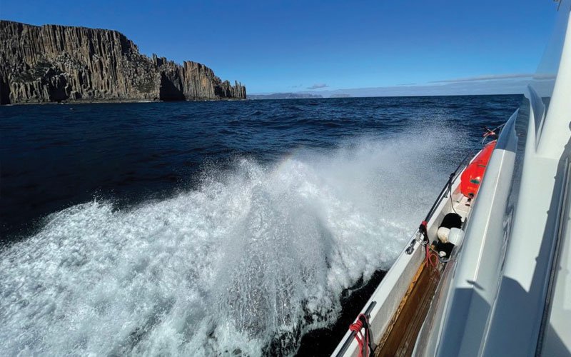 Sailing yacht equipped with Turtle-Pac flexible bladder tanks and liferaft gear, crew handling marine safety equipment during offshore sailing in rough seas and polar environments.