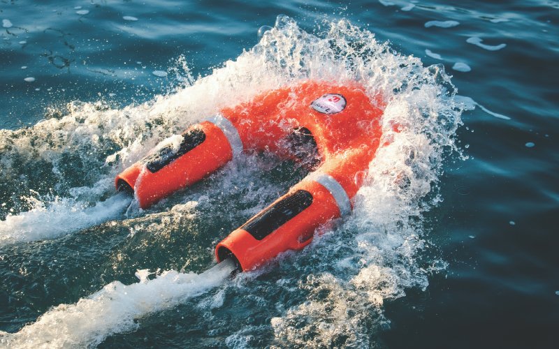 An orange plastic life buoy from Versilia Marine Service, tossed in the water and ready to assist in an emergency rescue.