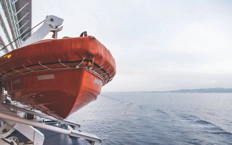 n orange lifeboat from Versilia Marine Service, hanging from the deck of a large passenger ship, ready for emergency use