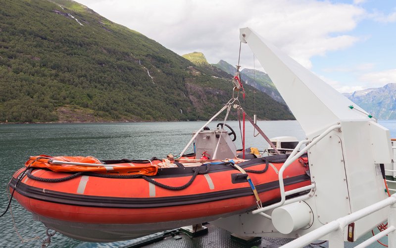 n orange lifeboat from Versilia Marine Service, hanging from the deck of a large passenger ship, ready for emergency use