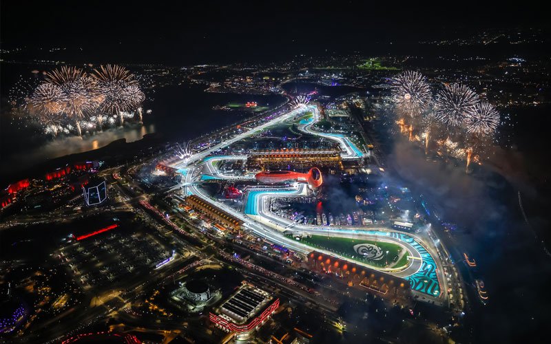 Aerial night view of Yas Marina Circuit during a Formula 1 event with fireworks lighting the sky.