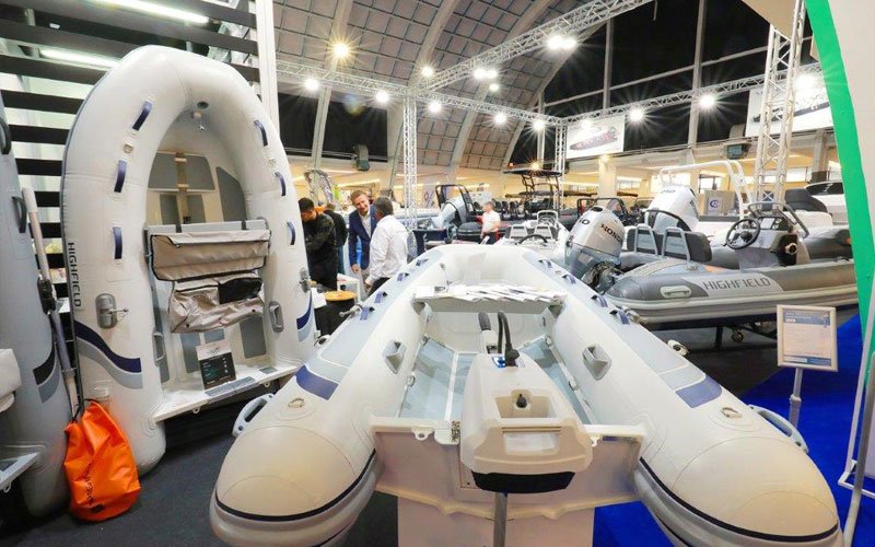 Zagreb Boat Show indoor scene with inflatable boats on display, including Highfield models, and people engaging with exhibitors